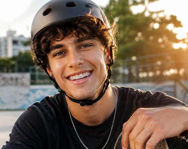 Jovem sorrindo de capacete no skatepark